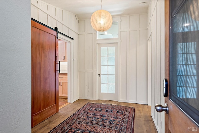 doorway to outside with a barn door and light hardwood / wood-style floors