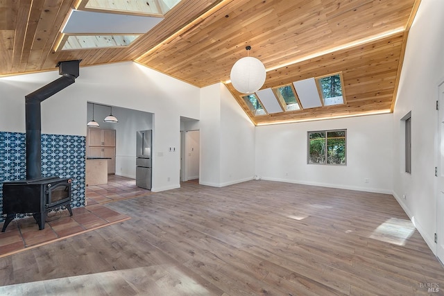 unfurnished living room with a wood stove, a skylight, high vaulted ceiling, wood-type flooring, and wood ceiling