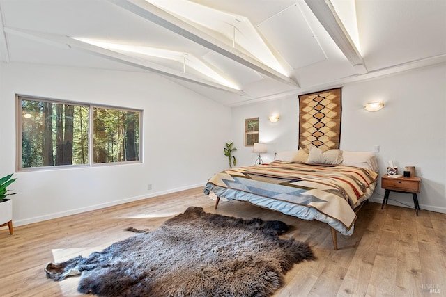 bedroom with lofted ceiling with beams and light wood-type flooring