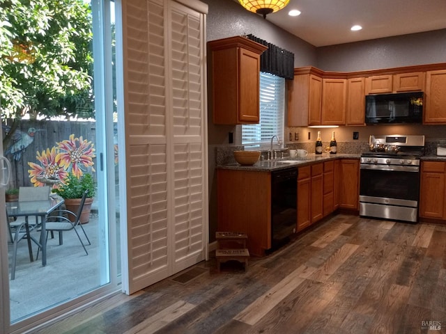 kitchen with dark hardwood / wood-style floors, dark stone countertops, black appliances, and sink