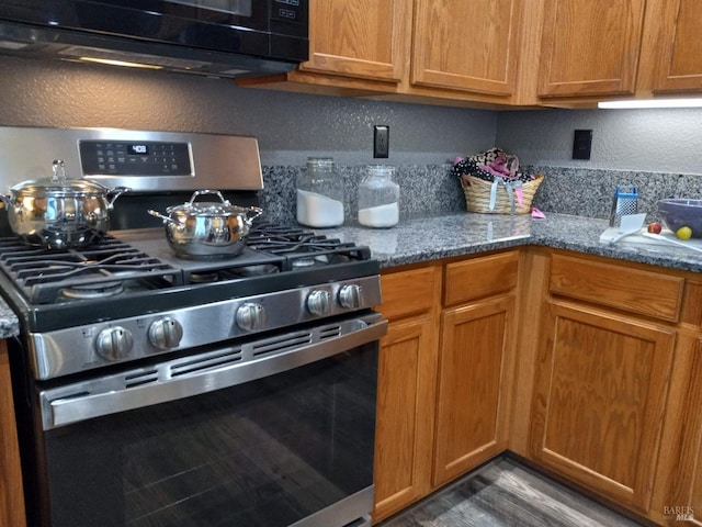 kitchen with dark wood-type flooring, light stone counters, and stainless steel gas stove