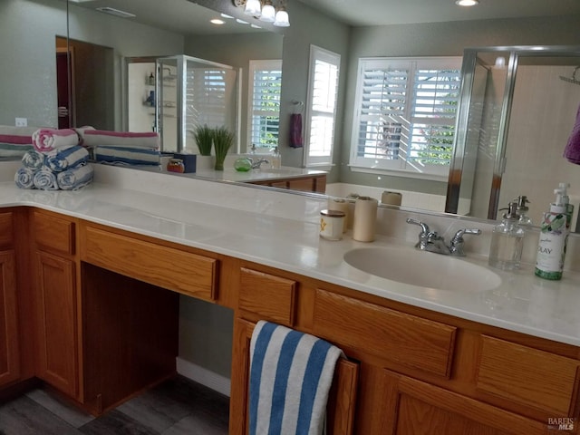 bathroom featuring a shower with door and vanity