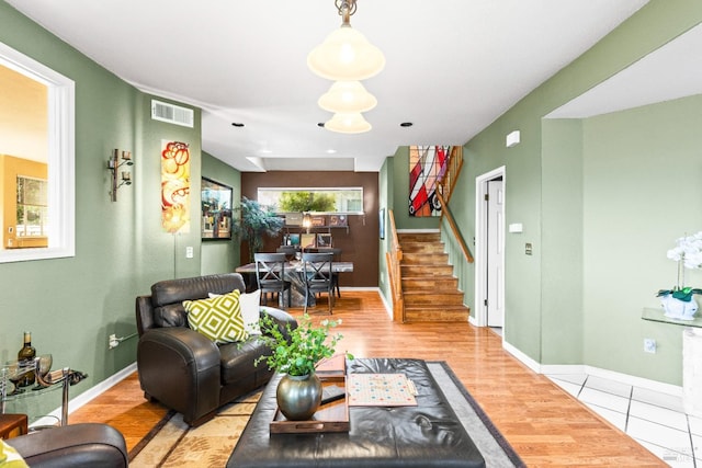 living area featuring visible vents, baseboards, wood finished floors, and stairway