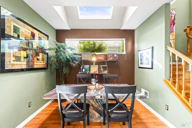 dining room featuring stairway, wood finished floors, visible vents, baseboards, and a skylight