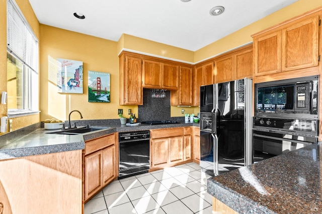 kitchen with black appliances, a sink, dark countertops, a peninsula, and light tile patterned flooring