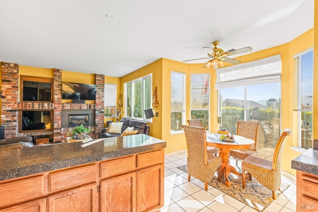 kitchen with light tile patterned floors, open floor plan, a brick fireplace, and ceiling fan