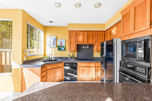 kitchen with dark countertops, backsplash, recessed lighting, black appliances, and a sink