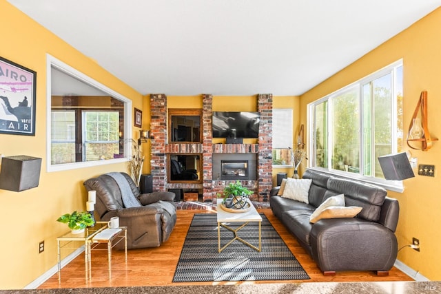 living room featuring wood finished floors, a fireplace, baseboards, and a wealth of natural light