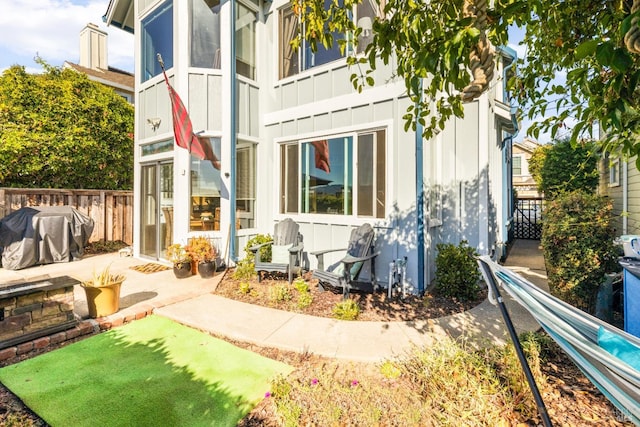 view of property exterior featuring a patio area, board and batten siding, and fence