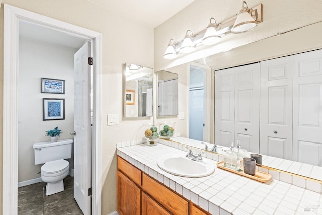 bathroom with vanity, toilet, baseboards, and a closet