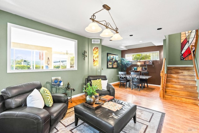 living area featuring stairs, wood finished floors, visible vents, and baseboards