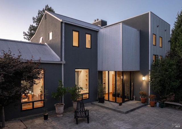 back house at dusk with a patio area