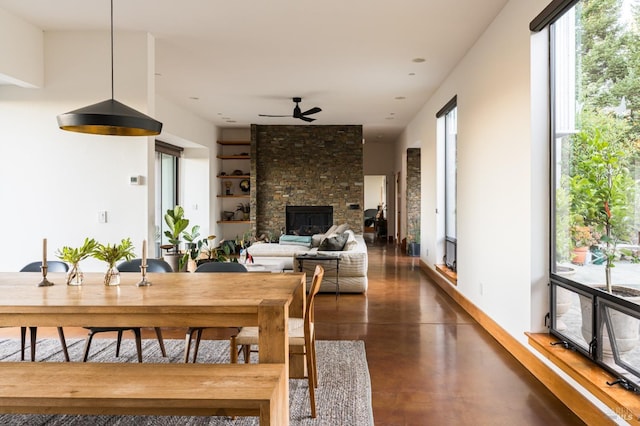 dining area with ceiling fan, a fireplace, and built in shelves