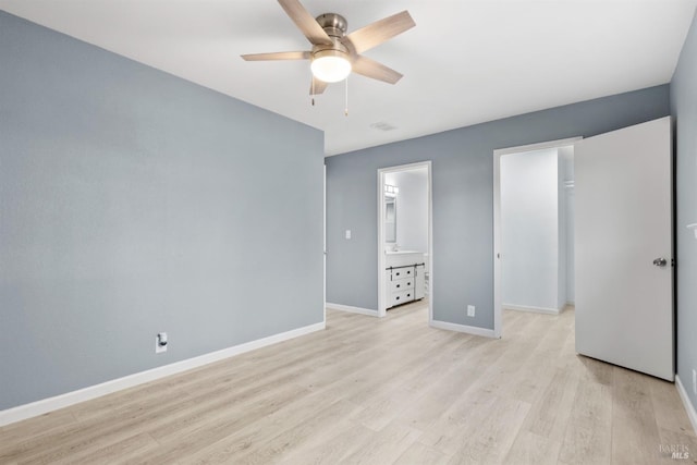 unfurnished bedroom with light wood-type flooring, ensuite bath, ceiling fan, and a spacious closet