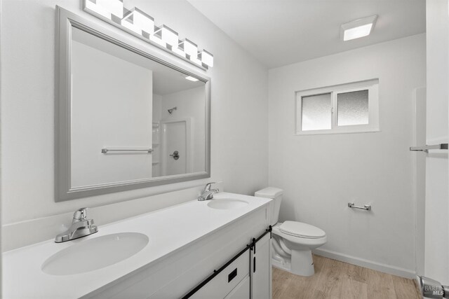 bathroom with walk in shower, vanity, hardwood / wood-style flooring, and toilet