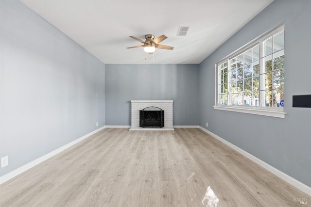 unfurnished living room with a brick fireplace, ceiling fan, and light wood-type flooring