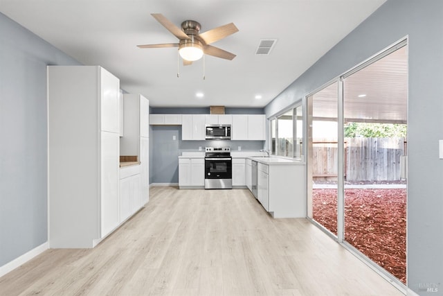 kitchen with stainless steel appliances, light wood-type flooring, sink, white cabinets, and ceiling fan