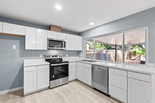 kitchen with white cabinets, light hardwood / wood-style floors, appliances with stainless steel finishes, and sink