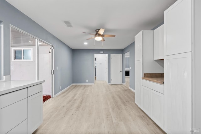 kitchen with light hardwood / wood-style flooring, ceiling fan, and white cabinets