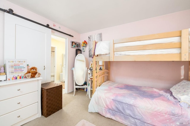 bedroom with light carpet and a barn door