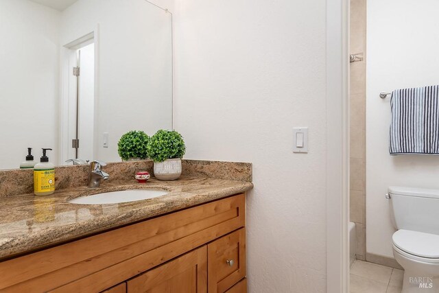 full bath with toilet, vanity, and tile patterned flooring