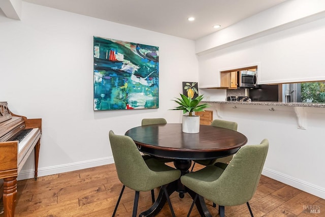 dining area with baseboards, light wood-type flooring, and recessed lighting