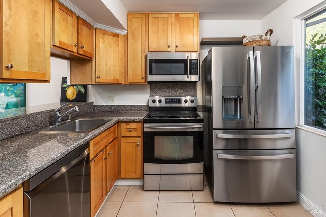 kitchen with light tile patterned flooring, appliances with stainless steel finishes, sink, and dark stone counters