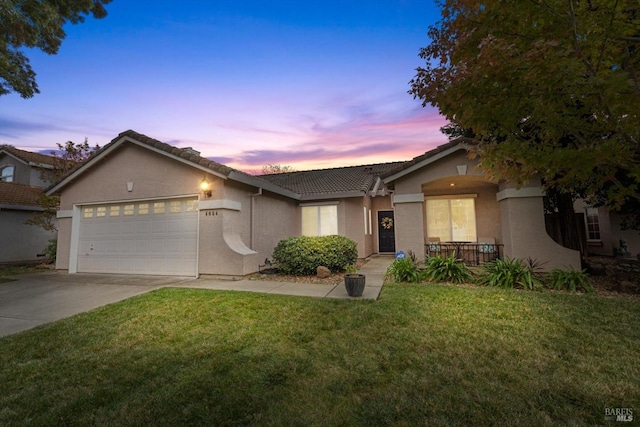 ranch-style home featuring a garage and a lawn