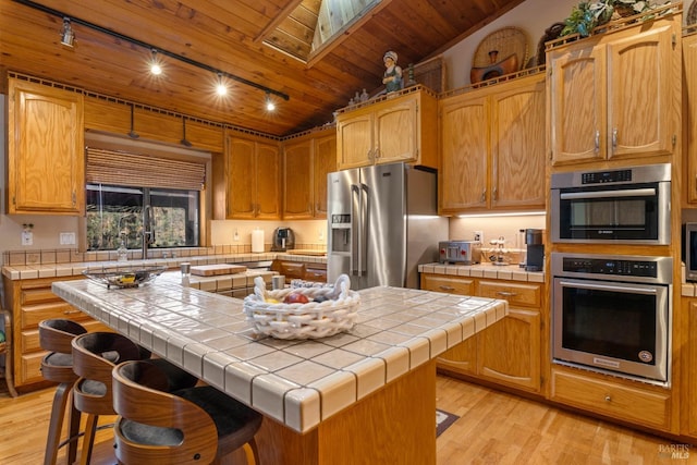 kitchen with tile countertops, a center island, stainless steel appliances, and rail lighting