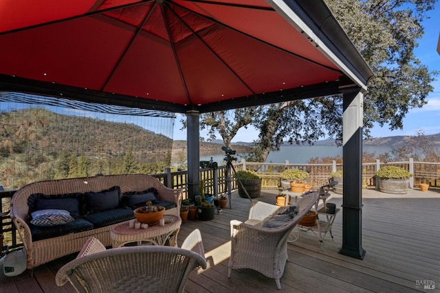 wooden terrace with a gazebo, an outdoor hangout area, and a water and mountain view