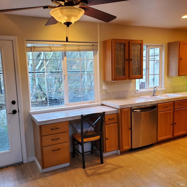 kitchen with ceiling fan, sink, tile countertops, dishwasher, and light hardwood / wood-style floors