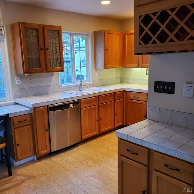 kitchen with tile counters, dishwasher, and sink