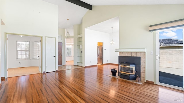 unfurnished living room with high vaulted ceiling, a wealth of natural light, beam ceiling, and wood finished floors