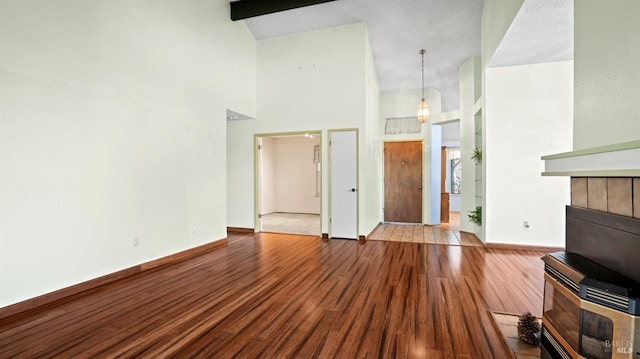 unfurnished living room with beamed ceiling, high vaulted ceiling, and light wood-type flooring