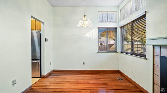 unfurnished dining area with light hardwood / wood-style floors, a tile fireplace, and a chandelier