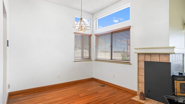 unfurnished living room with a healthy amount of sunlight, a textured ceiling, baseboards, and wood finished floors