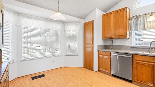 kitchen with a sink, visible vents, vaulted ceiling, stainless steel dishwasher, and brown cabinets