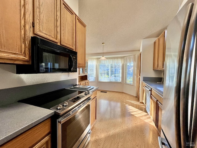 kitchen with pendant lighting, appliances with stainless steel finishes, a textured ceiling, and light wood-type flooring