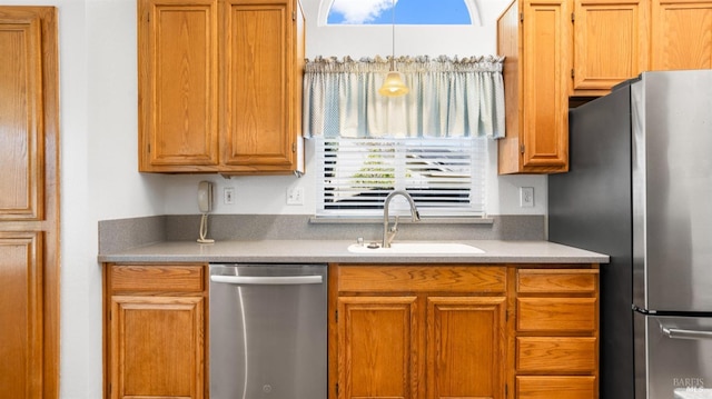 kitchen featuring stainless steel appliances, light countertops, brown cabinetry, and a sink