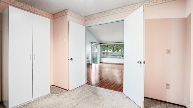 unfurnished bedroom featuring vaulted ceiling, light carpet, and a closet