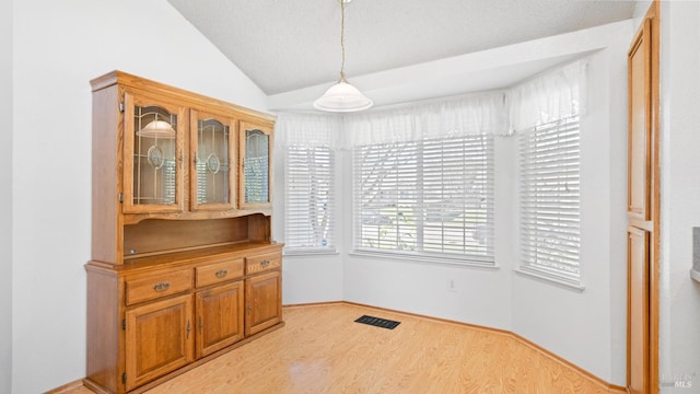 dining area with lofted ceiling, visible vents, and light wood-style floors