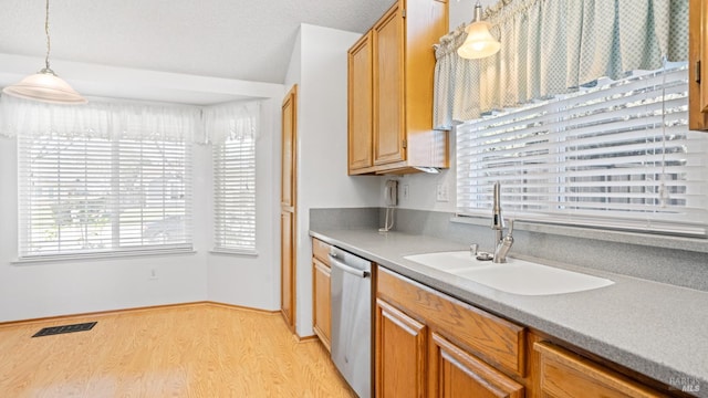 kitchen featuring a sink, visible vents, light wood-style floors, hanging light fixtures, and dishwasher