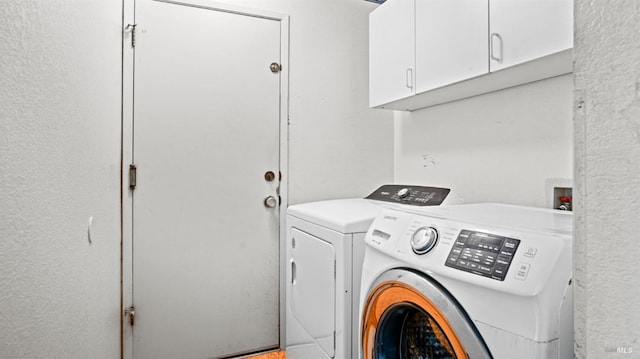 clothes washing area with cabinets and washer and dryer