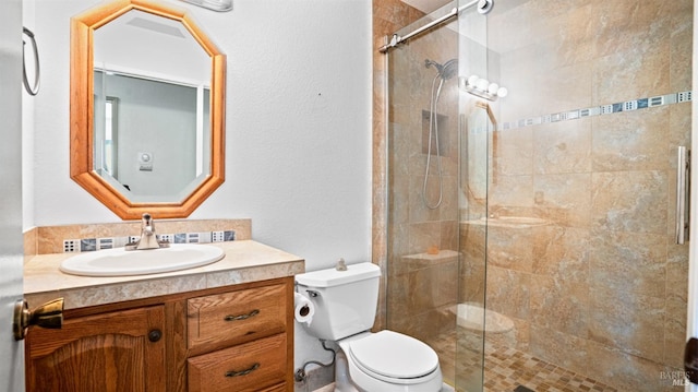 bathroom with a shower with door, vanity, and toilet