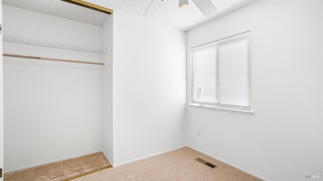 interior space with a textured ceiling, carpet floors, multiple windows, and visible vents