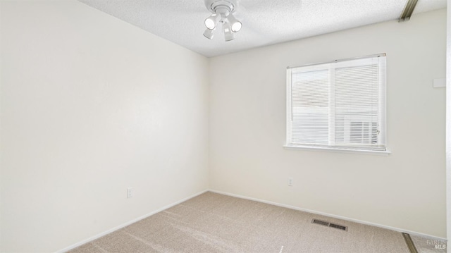 carpeted spare room with visible vents, ceiling fan, a textured ceiling, and baseboards