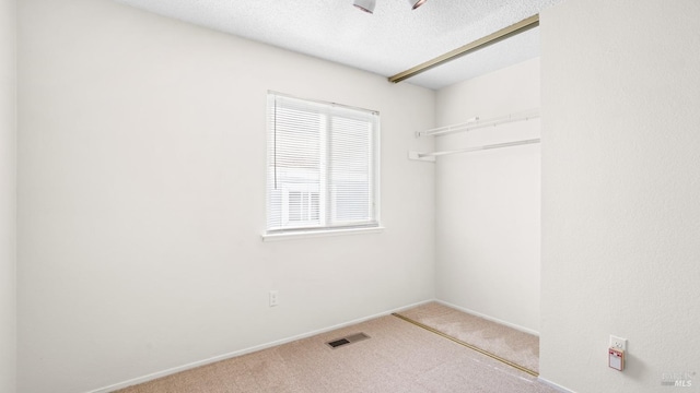 clothes washing area with carpet floors, visible vents, a textured ceiling, and baseboards