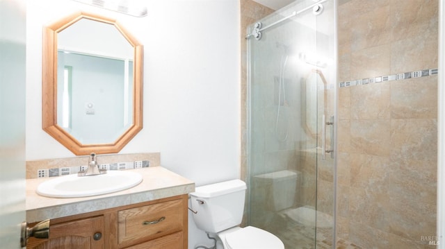 bathroom featuring toilet, a shower stall, and vanity