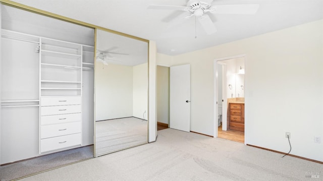 unfurnished bedroom with a closet, light colored carpet, ceiling fan, and ensuite bath