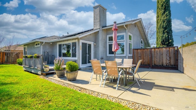 back of house with a chimney, a patio area, a fenced backyard, and a lawn